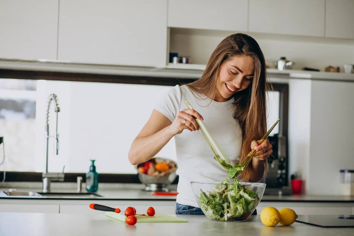 young woman making salad in the kitchen
