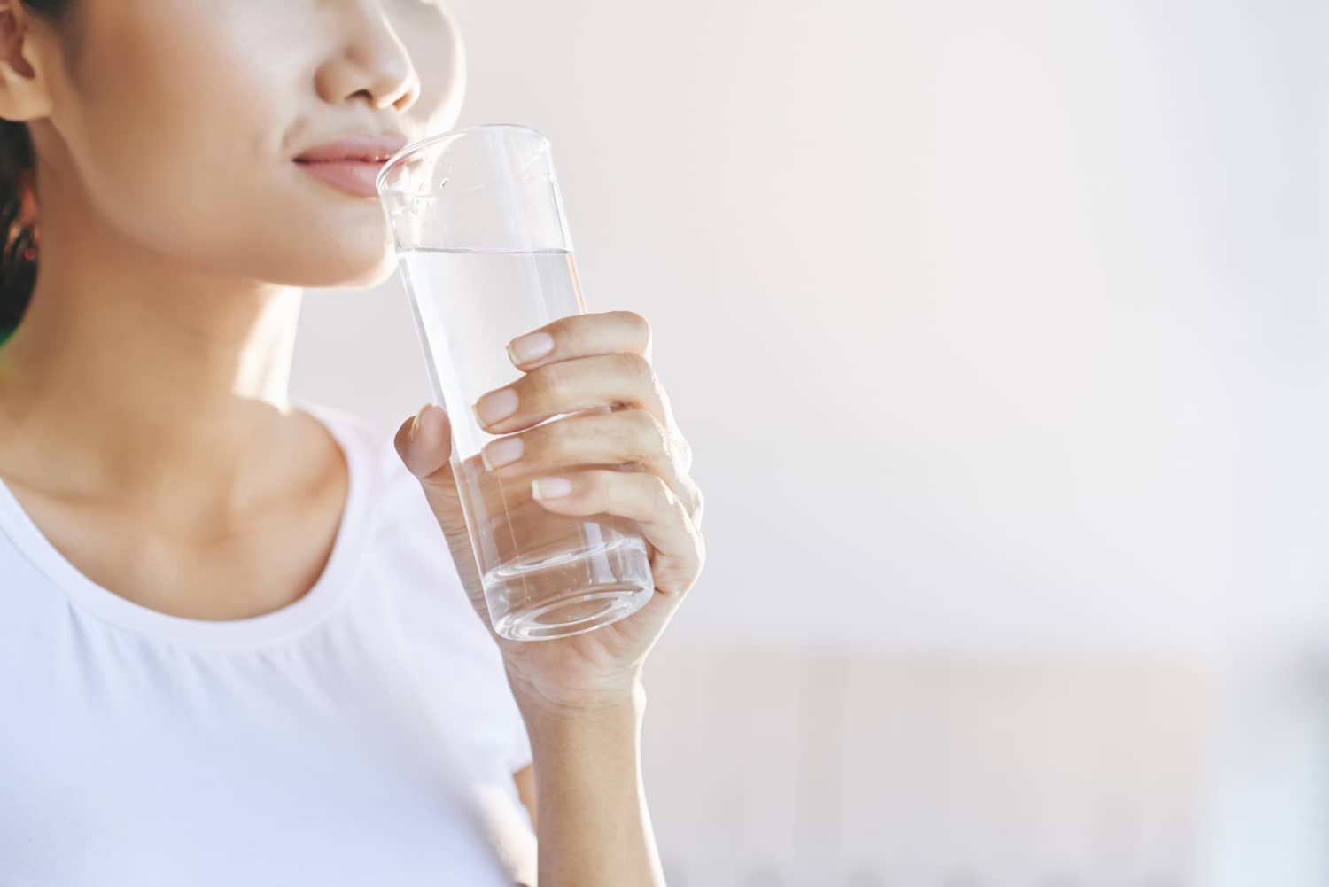 Unrecognizable woman carrying glass of water to mouth