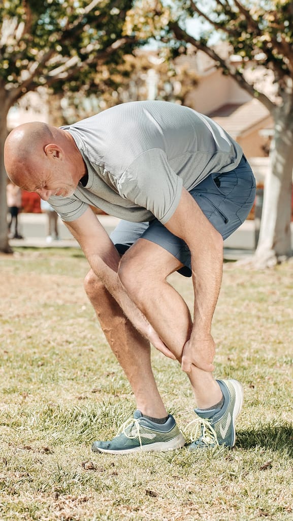 A man with bald head in bending position due to pain in sprained ankle