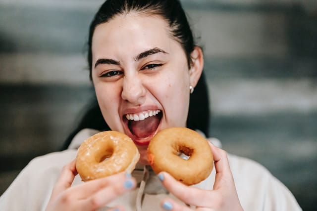 a girl excited to bite two donuts together 