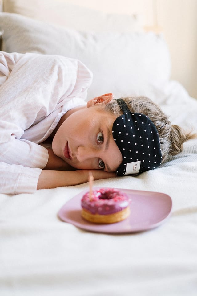 a girl in lying position staring at a donut in a plate